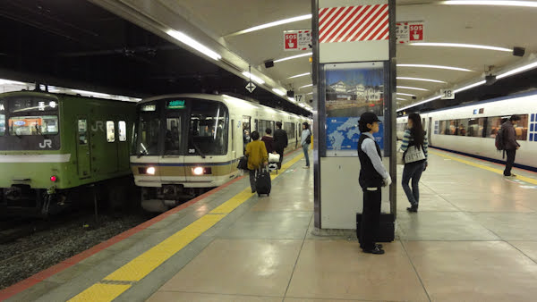 a train platform with multiple trains on various tracks